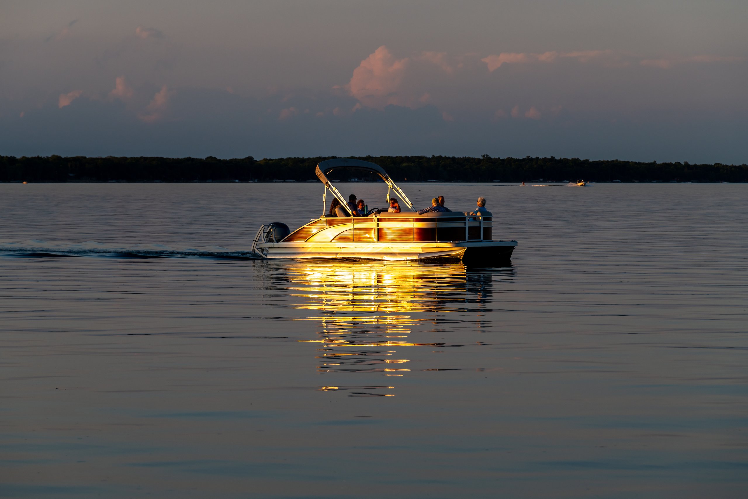 Otter Tail Lake, Minnesota USA July 10, 2022 People on a pontoon boat on Otter Tail Lake at sunset in rural Minnesota.