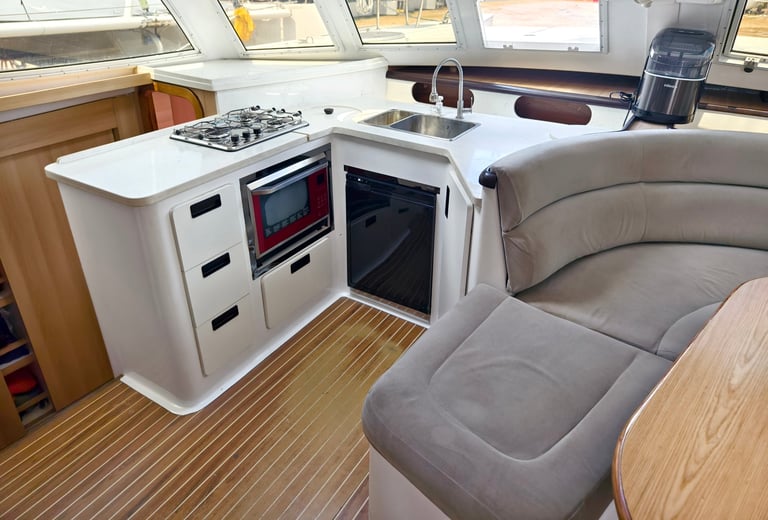 A cozy living room and kitchen featuring a stylish curved couch and a table located on sailing boat.