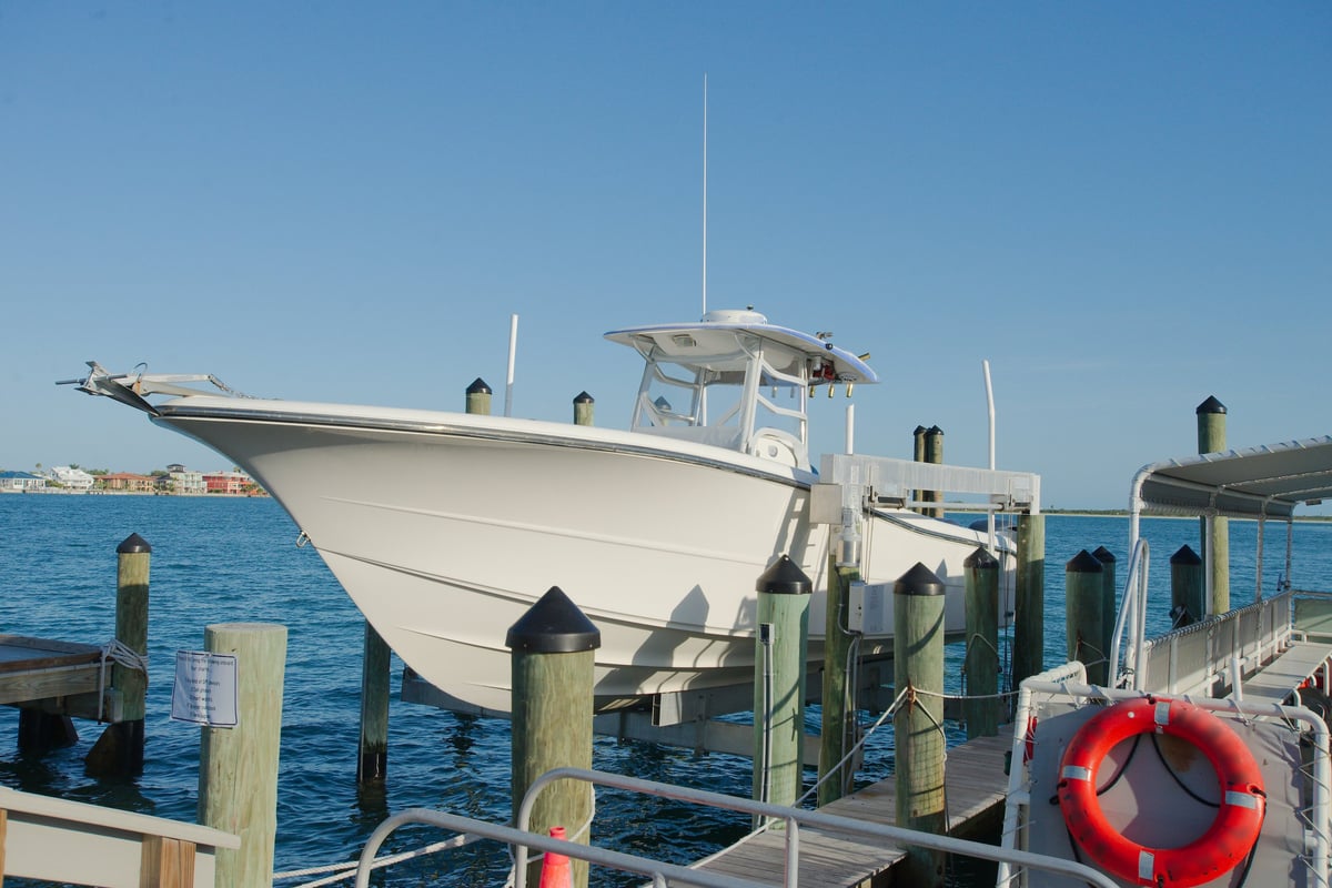 Boat hoisted at marina for maintenance above calm waters